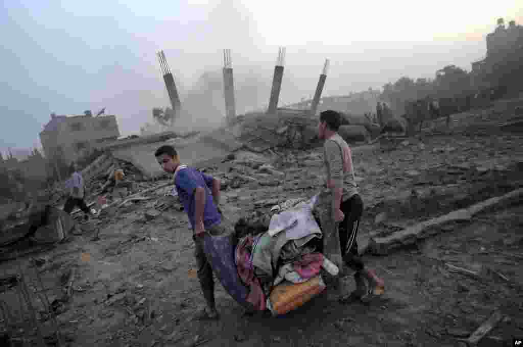 Palestinians try to salvage what they can from the rubble of a house destroyed by an overnight Israeli airstrike in Gaza City, July 8, 2014. 