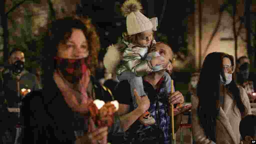 Un padre cuida a su hija mientras asisten a la misa ortodoxa de Pascua de medianoche frente a la catedral Alexander Nevsky, en Sofía, Bulgaria, este domingo 19 de abril de 2020.