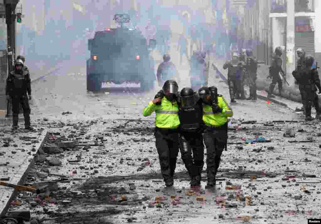 La policía antidisturbios ayuda a un colega herido durante las protestas.