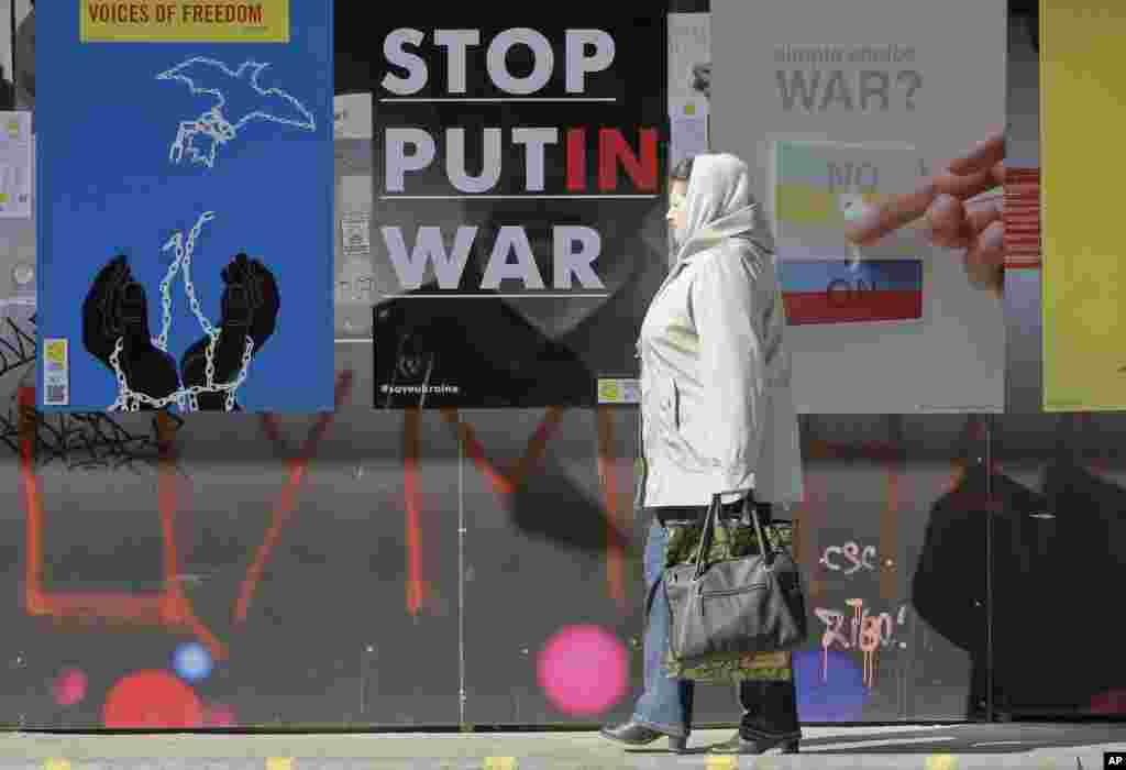 Seorang perempuan melewati poster-poster yang menyatakan dukungan pada Ukraina selama kampanye poster internasional di Kyiv (12/3). (AP/Efrem Lukatsky)