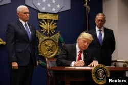 FILE - President Donald Trump signs the initial executive order for a U.S. travel ban, Jan. 27, 2017, at the Pentagon.