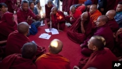 Activist known as Ko Kyaw, left background in blue pants, gestures during a meeting with protesting Buddhist monks who occupy the office entrance to the Chinese copper mine company Wan Bao Co. Ltd in northwestern Myanmar, Wednesday, Nov 28, 2012.
