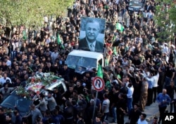 Mourners take the coffin of former Iraq President Jalal Talabani, seen in the poster, for burial during his funeral procession in Sulaimaniyah, 260 kilometers (160 miles) northeast of Baghdad, Iraq, Oct. 6, 2017.