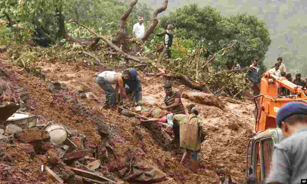 Rescue workers remove the body of a victim in Malin village, Wednesday, July 30, 2014.