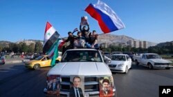 Syrian government supporters wave Syrian, Iranian and Russian flags as they chant slogans against U.S. President Trump during demonstrations following a wave of U.S., British and French military strikes.