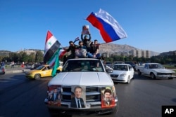 Pristalice sirijske vlade mašu sirijskim, iranskim i ruskim zastavama dok izvikuju slogane protiv predsjednika SAD Donalda Trumpa tokom demonstracija koje su uslijedile nakon serije američkih, britanskih i francuskih raketnih napada.
