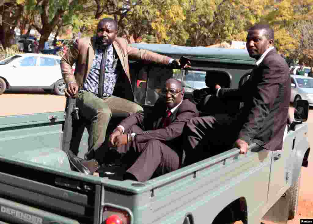 Douglas Mahiya, le secrétaire des anciens combattants du Zimbabwe est escorté par des détectives alors qu'il arrive à la cour de Harare, Zimbabwe, le 29 juillet 2016.