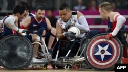 Japan's Shin Nakazato (C) holds onto the ball as Chuck Aoki of the US (L) closes in during the bronze medal Wheelchair Rugby match between USA and Japan, in London, September 9, 2012. 