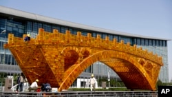 Workers install wires on a Golden Bridge of Silk Road structure outside the National Convention Center, the venue for the Belt and Road Forum for International Cooperation, in Beijing, April 18, 2017. Starting Sunday, Vladmir Putin of Russia, Recep Tayyip Erdogan of Turkey and Spain's Mariano Rajoy are among those attending a summit to discuss Xi's "One Belt, One Road" infrastructure investment program to stitch together the Eurasian continent.