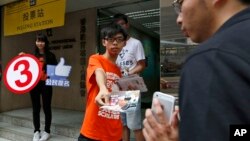 Joshua Wong, a student leader in the Occupy Central movement handouts leaflets near a polling station to urge people to vote on the last day for an unofficial referendum on democratic reform in Hong Kong, June 29, 2014.