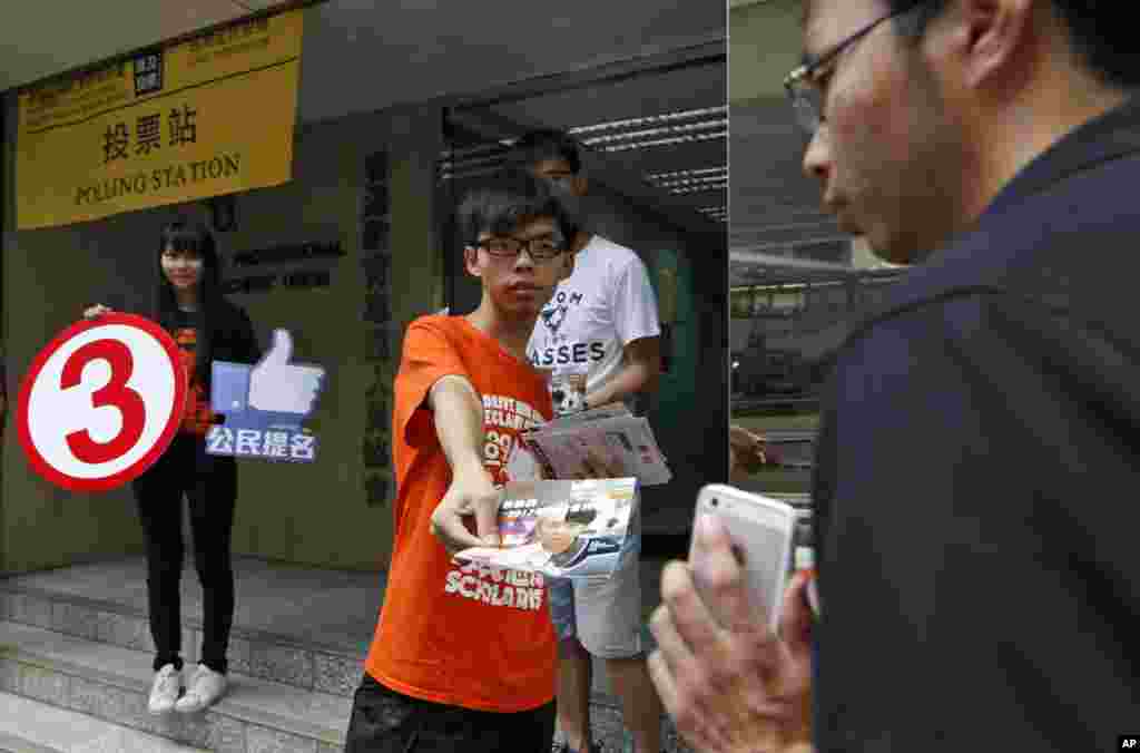 Joshua Wong, mahasiswa pemimpin gerakan Occupy Central membagikan brosur dekat tempat pemungutan suara untuk mendesak warga memilih dalam hari terakhir untuk referendum mengenai reformasi demokratik di Hong Kong (29/6).