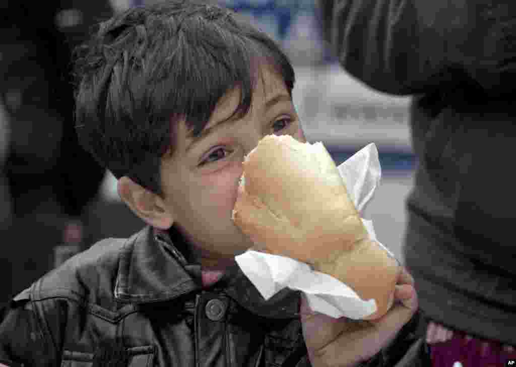 A homeless child bites on a loaf of bread outside the main railway station in Bucharest, Romania.