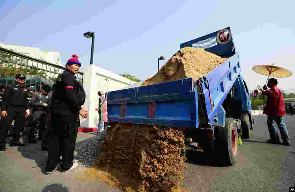 Pro-government supporters dump sand to build a barricade in front of the gate of National Anti-Corruption Commission office in Bangkok, Feb. 27, 2014. 