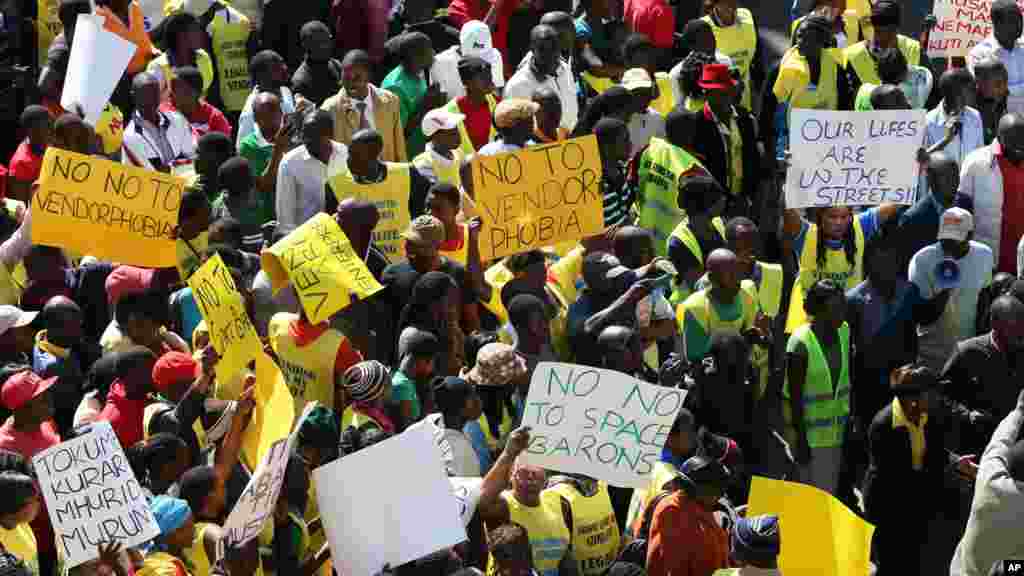 Zimbabwean vendors hold banners urging the government to stop their forced removals from the street during a demonstration in Harare, Wednesday, June, 24, 2015. Hundreds of vendors took to the streets of Harare demonstrating against an impending eviction from the streets.