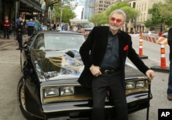 FILE - In this March 12, 2016, file photo, Burt Reynolds sits on a 1977 Pontiac Trans-Am at the world premiere of "The Bandit" at the Paramount Theatre during the South by Southwest Film Festival in Austin, Texas. Hundreds of fans in Trans Ams made it to Atlanta to celebrate the 40th anniversary of "Smokey and the Bandit" this weekend.