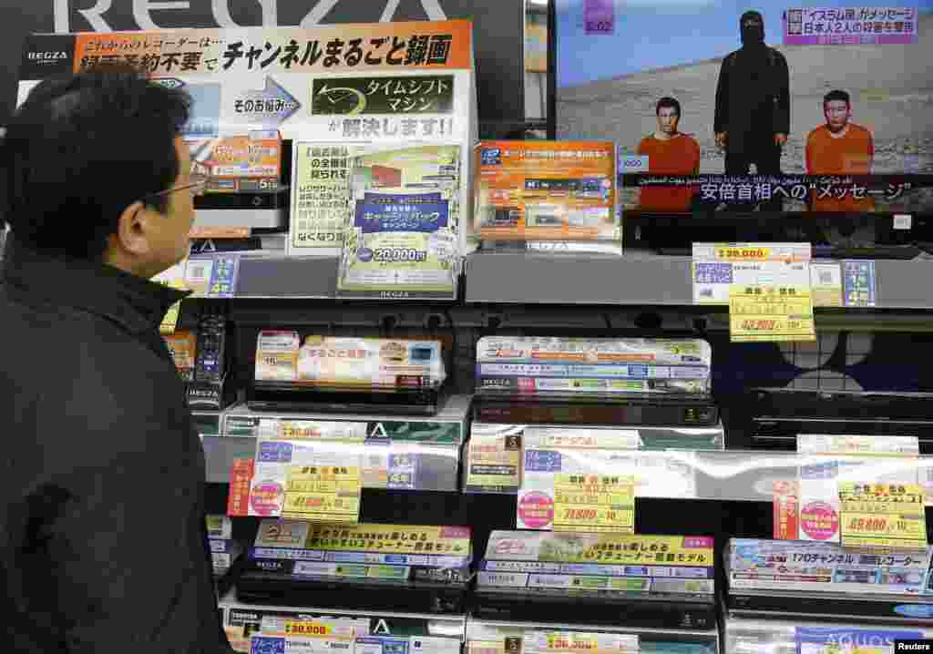 A man watches a news program about an Islamic State video purporting to show two Japanese captives, at an electronics store in Tokyo, Japan, Jan. 20, 2015.