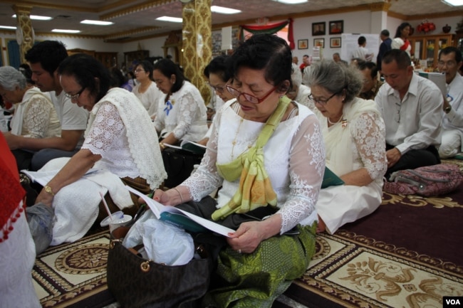 ពុទ្ធបរិស័ទអាននិងផ្ទៀងគម្ពីរព្រះត្រៃបិតក នៅពេលព្រះសង្ឃសូត្រក្នុងវត្ត មុនីសុតារាម រដ្ឋ មីនីសូតា សហរដ្ឋអាមេរិក កាលពីថ្ងៃអាទិត្យ ទី២៦ ខែ ឧសភា ឆ្នាំ ២០១៩ ។ (សាយ មុន្នី/VOA)