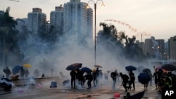 Protesters throw back tear gas canisters in Hong Kong on Monday, Aug. 5, 2019. (AP Photo/Kin Cheung)