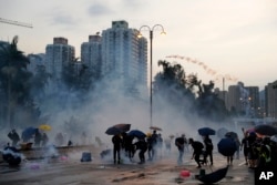 Protesters throw back tear gas canisters in Hong Kong on Monday, Aug. 5, 2019. (AP Photo/Kin Cheung)