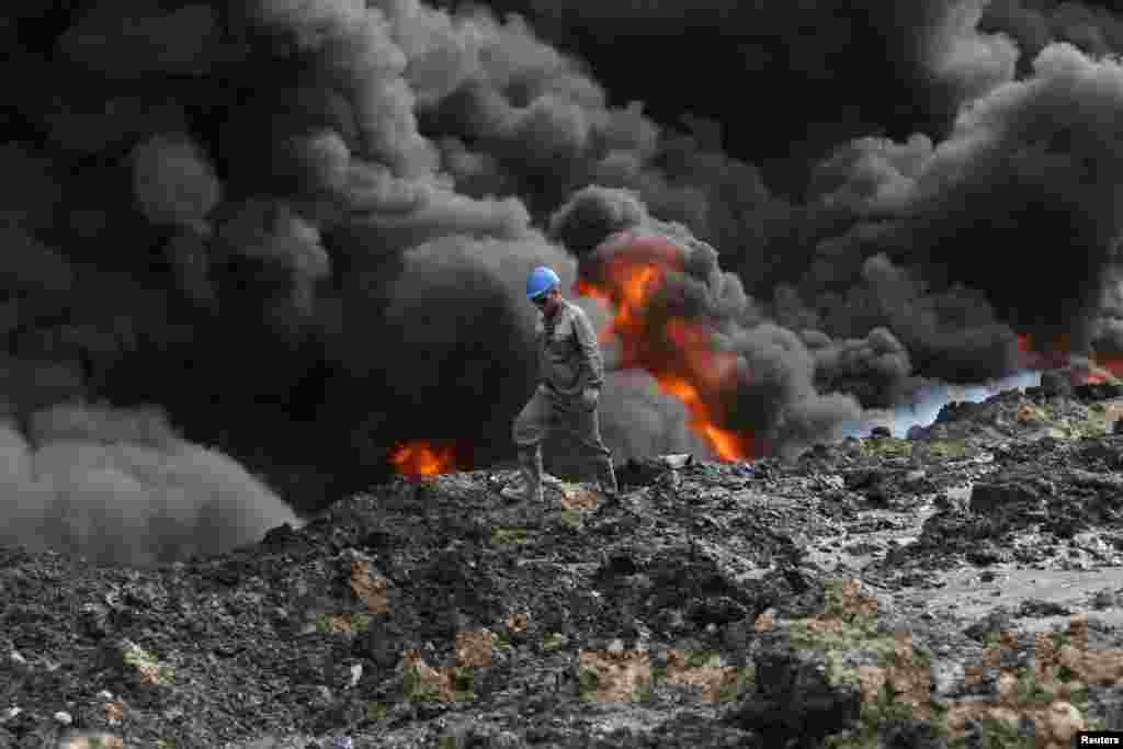 Asap tebal mengepul dari sumur minyak di Qayyara yang dibakar oleh militan ISIS untuk menghambat laju pasukan Irak ke Mosul.