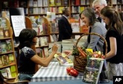 Ibu Negara Michelle Obama menandatangani bukunya “American Grown: The Story of the White House Kitchen Garden and Garden Accross America,” di toko buku Politics and Prose, di Washington, 7 Mei 2013.