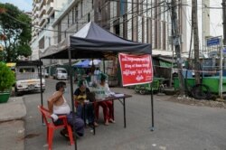 Sukrelawan duduk di pembatas darurat untuk memblokir akses ke jalan kecil menuju kompleks perumahan, di Yangon, Myanmar, saat diberlakukannya restriksi di tengah pandemi Covid-19, 11 September 2020.