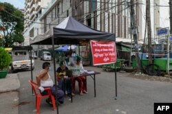 Sukrelawan duduk di pembatas darurat untuk memblokir akses ke jalan kecil menuju kompleks perumahan, di Yangon, Myanmar, saat diberlakukannya restriksi di tengah pandemi Covid-19, 11 September 2020.