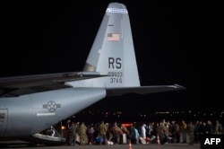 Pengungsi Afghanistan keluar dari pesawat angkatan udara AS setibanya di bandara Internasional Pristina dekat Pristina, 29 Agustus 2021.