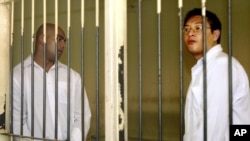 Australian Andrew Chan, right, and, and Myuran Sukumaran, left, stand inside a holding cell after their trial at a court in Denpasar, Bali, Indonesia, Tuesday, Feb. 14, 2006.