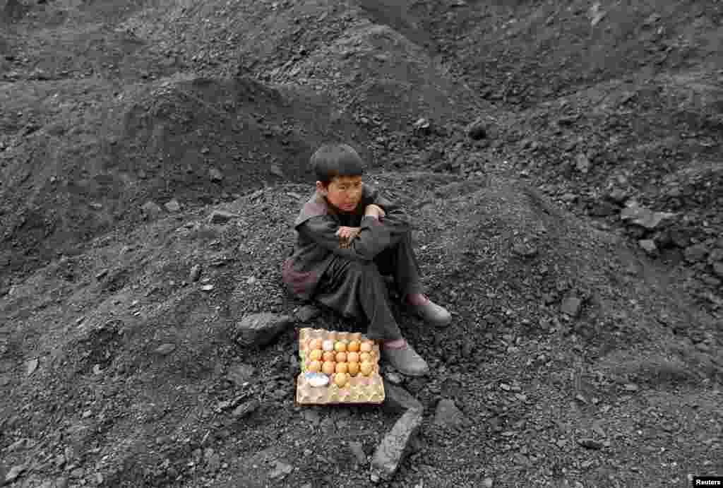 An Afghan boy selling boiled eggs waits for customers at a coal dump site on the outskirts of Kabul.