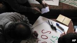Syrian activists prepare signs for protests at a house in a neighborhood in Damascus, Syria.