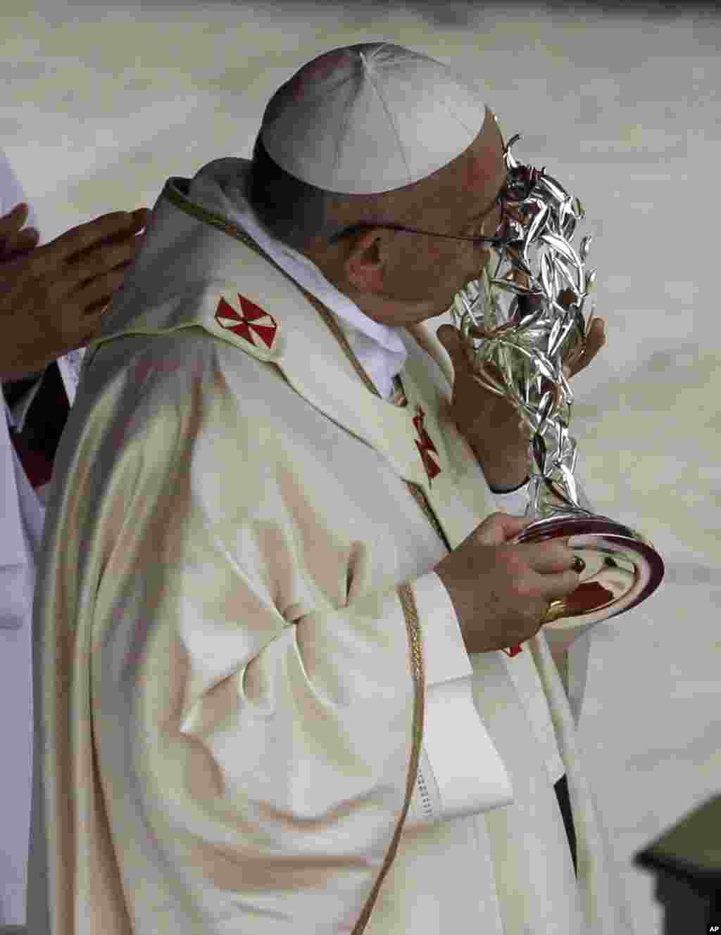 Paus Fransiskus mencium barang peninggalan milik Yohanes Paulus ke-2 dalam sebuah upacara di Lapangan Santo Petrus di Vatikan, 27 April 2014.