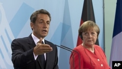 French President Nicolas Sarkozy and German Chancellor Angela Merkel brief the media at a news conference after their meeting at the chancellery in Berlin, June 17, 2011