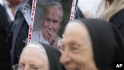 A picture of late Pope John Paul II, is framed by two nuns prior to the start of the Easter mass celebrated by Pope Benedict XVI in St. Peter's square, at the Vatican, April 24, 2011