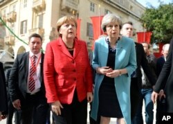 German Chancellor Angela Merkel, left, speaks with British Prime Minister Theresa May, right, as they walk with other EU leaders during an event at an EU summit in Valletta, Malta, on Friday, Feb. 3, 2017.