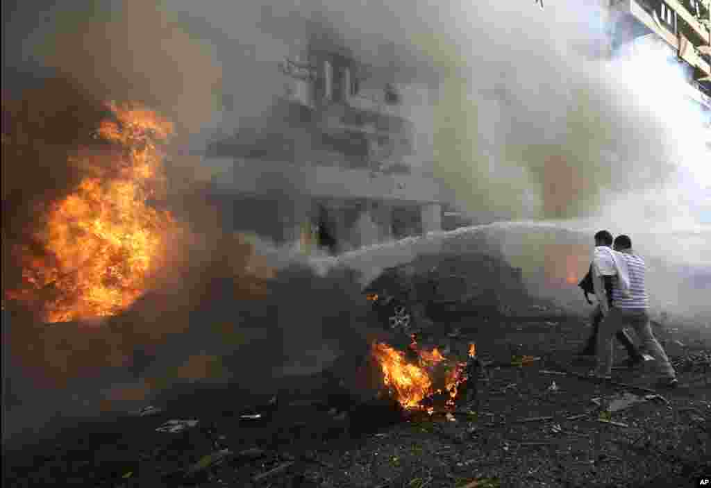 Two men react in front of burned cars after explosions near the Iranian embassy in Beirut, Nov. 19, 2013. 