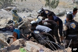 This photo provided by the Syrian Civil Defense White Helmets, which has been authenticated based on its contents and other AP reporting, shows Civil Defense workers searching through the rubble after airstrikes hit in Khan Sheikhoun.