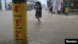 FILE - A flood warning gauge is seen along a flooded road after tropical storm Linfa hit the Philippines, July 6, 2015.