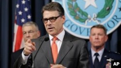 Gov. Rick Perry, center, speaks during a news conference in the Governor's press room in Austin, Texas, July 21, 2014. 