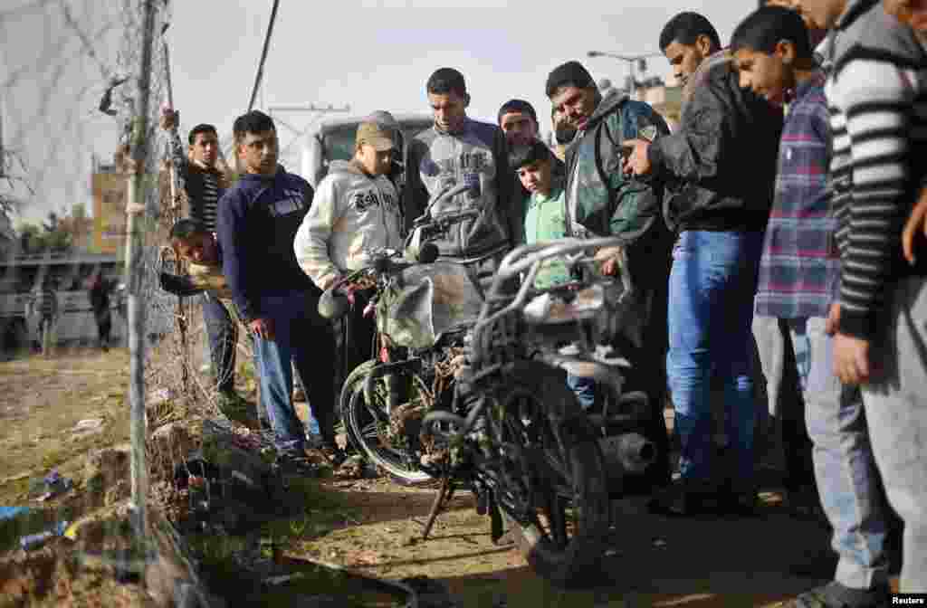 Palestinians look at a damaged motorcycle, which witnesses said was hit in an Israeli airstrike, northern Gaza Strip, Jan. 19, 2014.