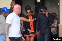 U.S. singer Beyonce (C) and her husband rapper Jay-Z (R), are escorted by bodyguards as they leave their hotel in Havana, April 4, 2013.