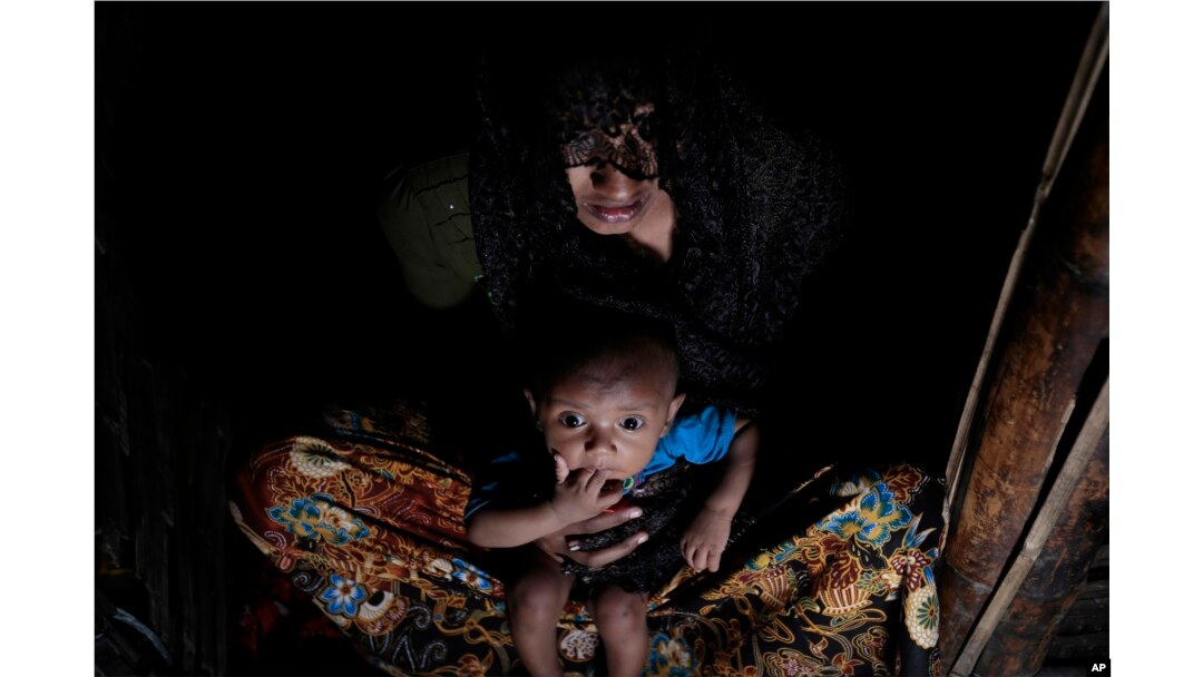 Mohsena Begum, a Rohingya who escaped to Bangladesh from Myanmar, holds her child and sits at the entrance of a room of an unregistered refugee camp in Teknaf, near Cox's Bazar, a southern coastal district south of Dhaka, Bangladesh, Dec. 2, 2016.