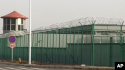 FILE - A guard tower and barbed wire fences are seen around a facility in the Kunshan Industrial Park in Artux in western China's Xinjiang region. This is one of a growing number of internment camps in the Xinjiang region.