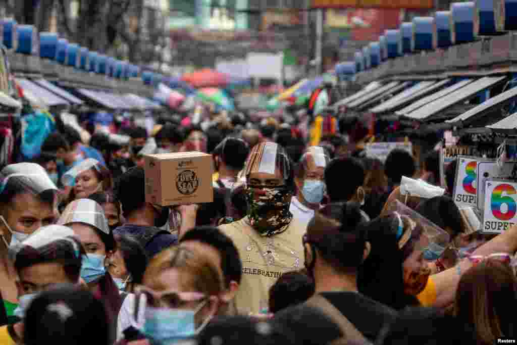 Filipinos wearing masks and face shields for protection against the coronavirus disease (COVID-19) walk along a street market in Manila, Philippines.