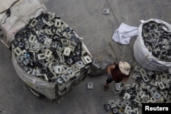 FILE - A worker distributes electronic waste at a government managed recycling center at the township of Guiyu in China's southern Guangdong province, June 10, 2015.