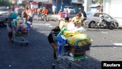 People with goods looted from a store walk pushing shopping carts along a street after a protest over a controversial pension reform plan, in Managua, Nicaragua, April 22, 2018.