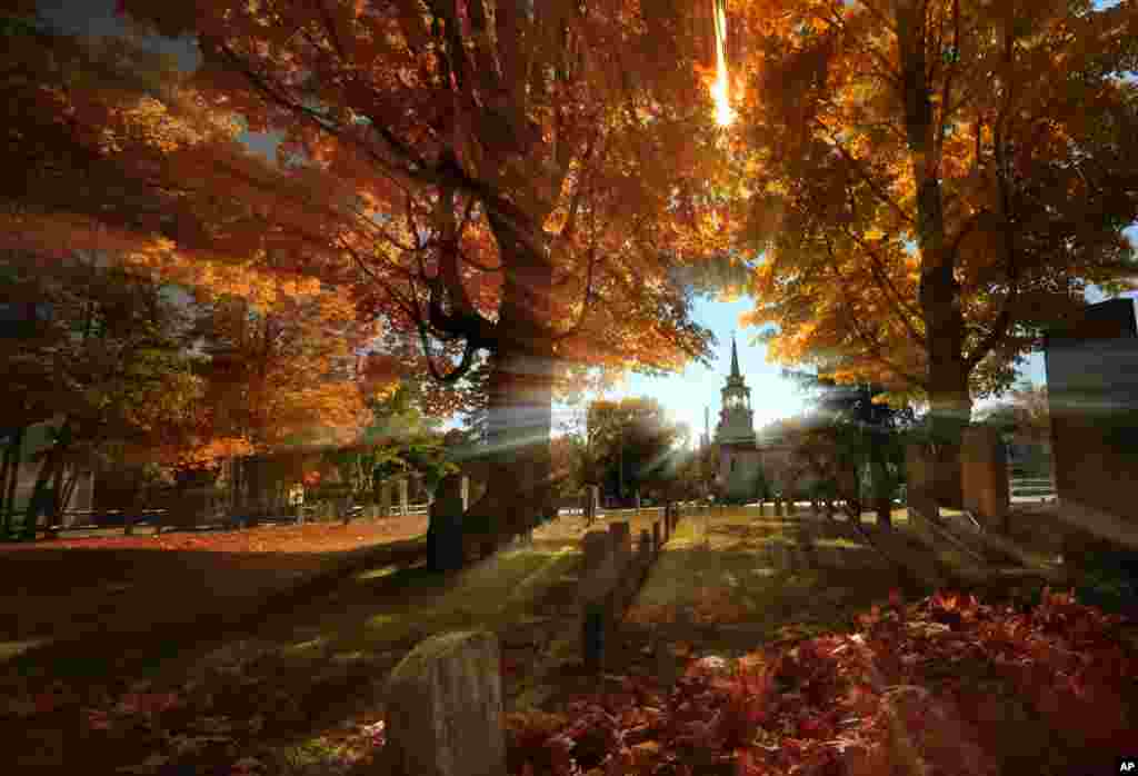 Fall colors peak on hardwood trees in a cemetery near the Congregational Church in Cumberland, Maine, USA, Oct. 10, 2016.