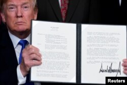 U.S. President Donald Trump holds a signed memorandum on intellectual property tariffs on high-tech goods from China, at the White House in Washington, March 22, 2018.