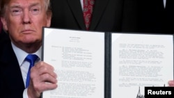 U.S. President Donald Trump holds a signed memorandum on intellectual property tariffs on high-tech goods from China, at the White House in Washington, March 22, 2018. 
