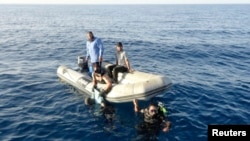 Anggota penjaga pantai Libya menemukan tubuh migran yang tenggelam di perairan Tripoli, 23 Agustus 2014.